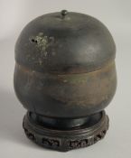AN EARLY BRONZE LIDDED JAR, together with a carved hardwood stand. Jar 16cm high (including cover)