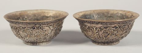 A PAIR OF CHINESE SILVERED METAL BOWLS, decorated with chilong, each with four-character marks to