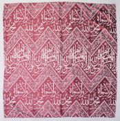 AN ISLAMIC RED GROUND TEXTILE, with alternating broad and narrow bands of calligraphy, 142cm