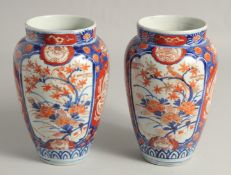 A PAIR OF JAPANESE IMARI PORCELAIN VASES, painted with panels of birds and flora, 21.5cm high.