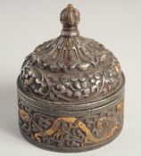 A TIBETAN SILVER INLAID CIRCULAR LIDDED STEEL BOX, with relief decoration of dragons and curling