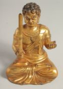 A GILT BRONZE MODEL OF A SEATED DEITY, sitting with legs crossed holding a sword in one hand and