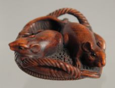 A 19TH/20TH CENTURY JAPANESE CARVED WOOD NETSUKE of two rats in a wicker basket, signed, 3.5cm.