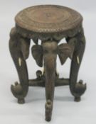 AN INDIAN CARVED HARDWOOD CIRCULAR STAND, the four legs carved as elephant heads with bone tusks,