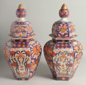 A LARGE PAIR OF JAPANESE IMARI PORCELAIN HEXAGONAL LIDDED URNS, painted with decorative panels of