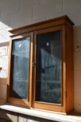 A pine two-door glazed hanging cabinet.