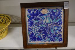 A pottery tile painted with fruit, in an oak frame.