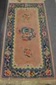 A Chinese rug, pink ground decorated with a dragon, 140cms x 70cms.