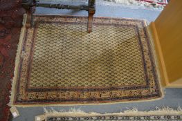 A Persian rug, beige ground with stylized Boteh decoration, 140cms x 105cms.