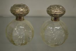 A pair of cut glass and silver topped scent bottles.