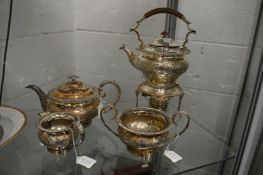A plated three-piece tea service and similar kettle on stand.