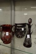 Two large ruby tinted cut-glass and etched glass jugs together with a similar jug and stopper.