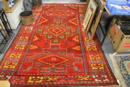 A large colourful red ground eastern carpet, 285cms x 190cms.