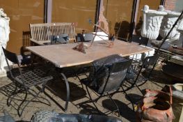 A wrought iron and wooden garden dining table with six folding wrought iron chairs and cushions.