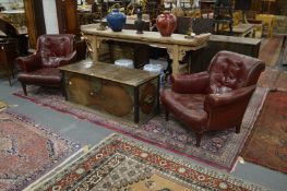 A pair of red leather upholstered club armchairs.