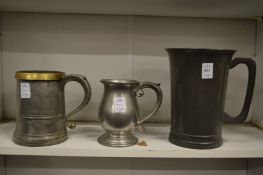A pewter half gallon tankard and two others.