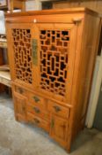 A Chinese soft wood cabinet with lattice work folding doors.
