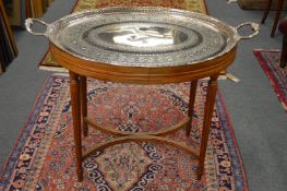 A good silver plated twin handled oval tray with engraved decoration on a mahogany stand.
