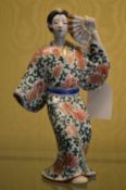 A Japanese Kutani figure of a woman holding a fan.