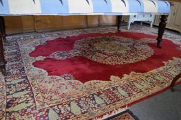 A large Kirman carpet, crimson ground with floral decoration, 355cms x 240cms.