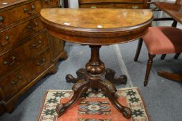 A Victorian walnut demi-lune foldover card table.