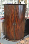 A George III mahogany bow front hanging corner cupboard.