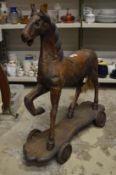 A large carved wooden horse on wheeled base.