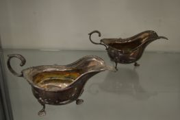 A pair of silver sauce boats and ladles.