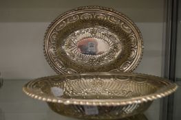 A pair of embossed white metal oval dishes.