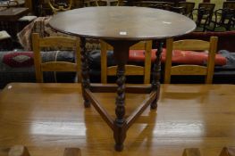 An oak circular occasional table on three barley twist columns.