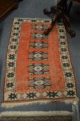 A small eastern rug, crimson ground with stylized decoration, 134cms x 87cms.