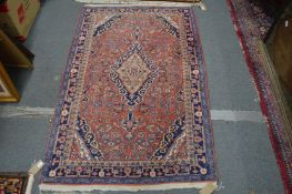 A small pink ground Persian design rug with floral decoration, 165cms x 105cms.