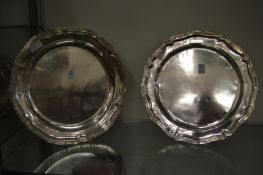 A pair of white metal wavy edged dishes.