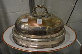 A plated meat dome and a porcelain dish.
