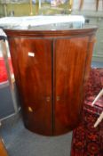A mahogany bow front hanging corner cupboard.