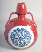 A CHINESE IRON-RED TWIN HANDLED MOON FLASK decorated with central blue and white yin-yang medallion,
