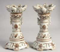 A PAIR OF CHINESE UNDERGLAZE RED AND WHITE PORCELAIN CANDLESTICKS, painted with characters, lotus,