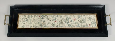 A CHINESE EMBROIDERED SILK TEXTILE, framed within a two handled tray, textile 48.5cm x 8.5cm.