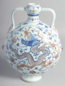 A CHINESE BLUE, WHITE, AND UNDERGLAZE RED TWIN HANDLED MOON FLASK painted with dragon and lotus, the