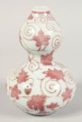 A CHINESE UNDERGLAZE RED PORCELAIN DOUBLE GOURD VASE with swirling vine and leaf pattern decoration.