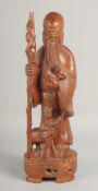 A LARGE CHINESE CARVED HARDWOOD FIGURE of an immortal holding a peach and a staff, 46.5cm high.