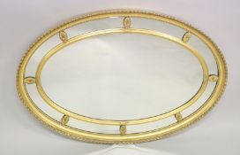A REGENCY DESIGN OVAL GILTWOOD WALL MIRROR with leaf carved border, ribbon and reed inner frame