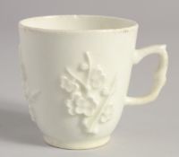 A BOW WHITE GLAZE COFFEE CUP with applied prunus decoration, having an elaborate handle.