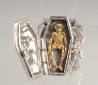 A HEAVY SILVER BAT'S WING COFFIN SHAPED RING opening to reveal a skeleton.