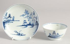 A LIVERPOOL TEABOWL AND SAUCER painted in blue with a river scene, with two huts and a rocky