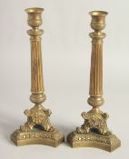 A PAIR OF EMPIRE ORNATE CANDLESTICKS on shaped triangular bases. 11.5ins high.