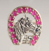 A SILVER AND FAUX RUBY HORSESHOE RING.