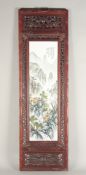 A CHINESE PORCELAIN PANEL, mountain scene with calligraphy in a pierced wooden frame. Panel 29ins