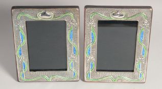 A PAIR OF ART NOUVEAU STYLE SILVER AND ENAMEL PHOTOGRAPH FRAMES. 7.5ins x 5.5ins.