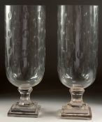 A PAIR OF CUT GLASS STORM LANTERNS on square stepped bases. 16ins high.